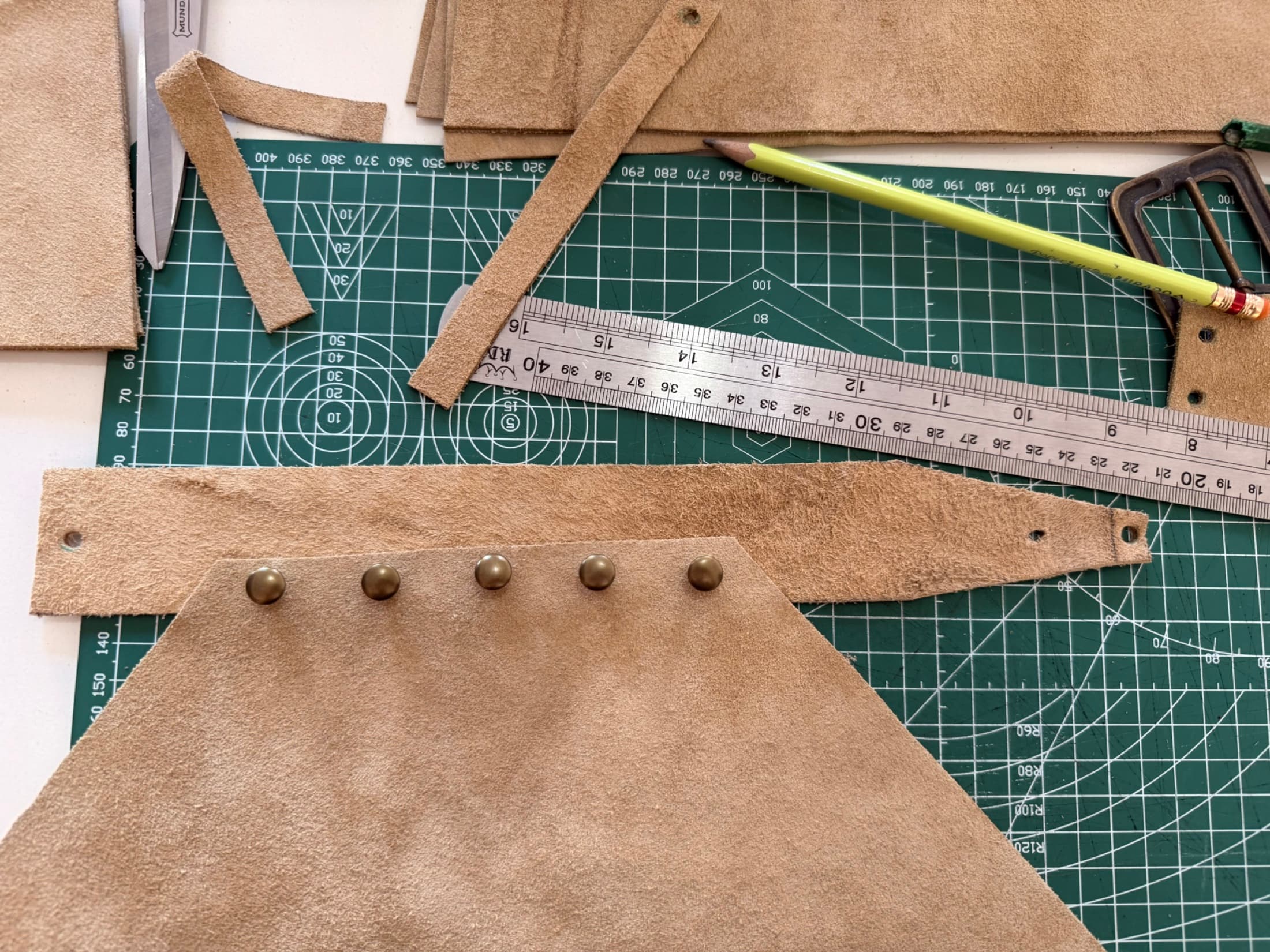Piezas de cuero, regla y lápiz durante el desarrollo de un nuevo diseño